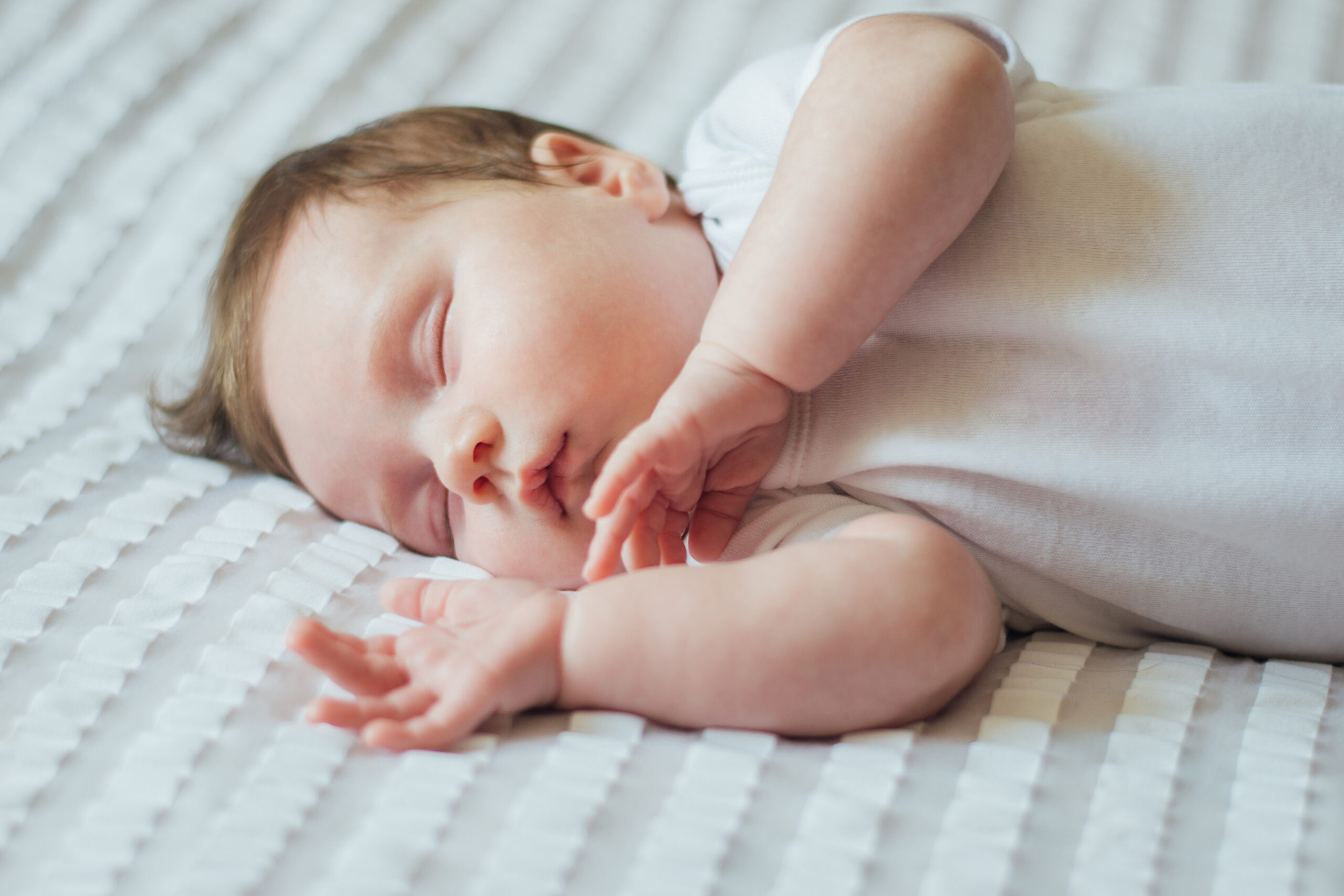 Cute infant child sleeping on white sheets